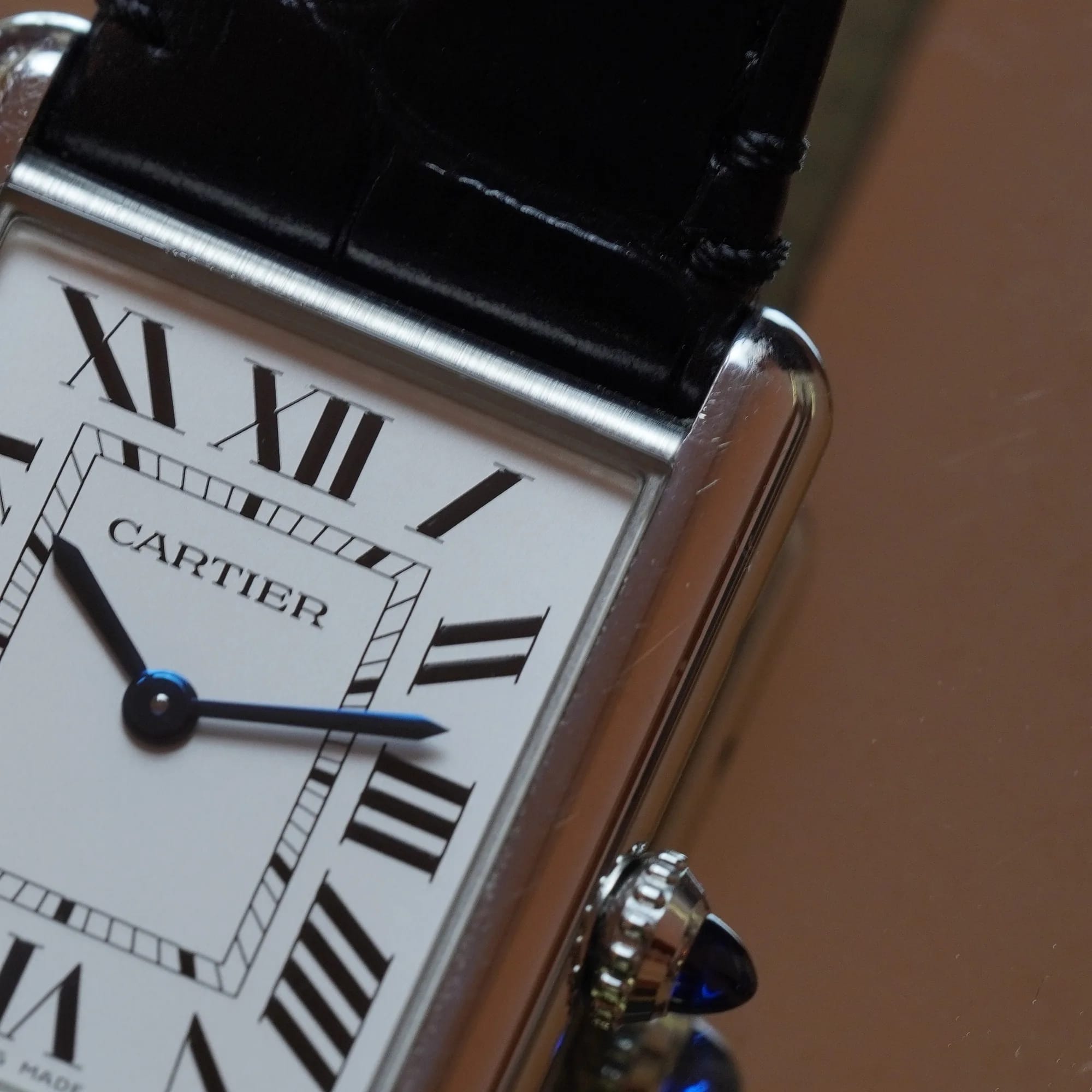 Close-up of the silvered dial with Roman numerals, blued sword hands and the crown with blue cabochon
