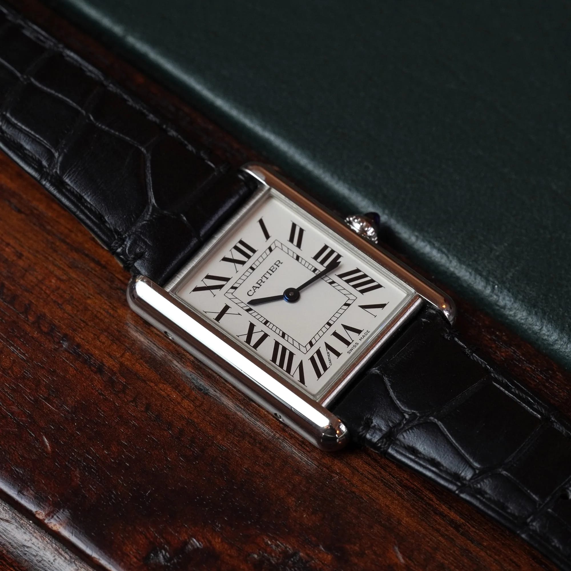 Cartier Tank Must at an angle on dark wood