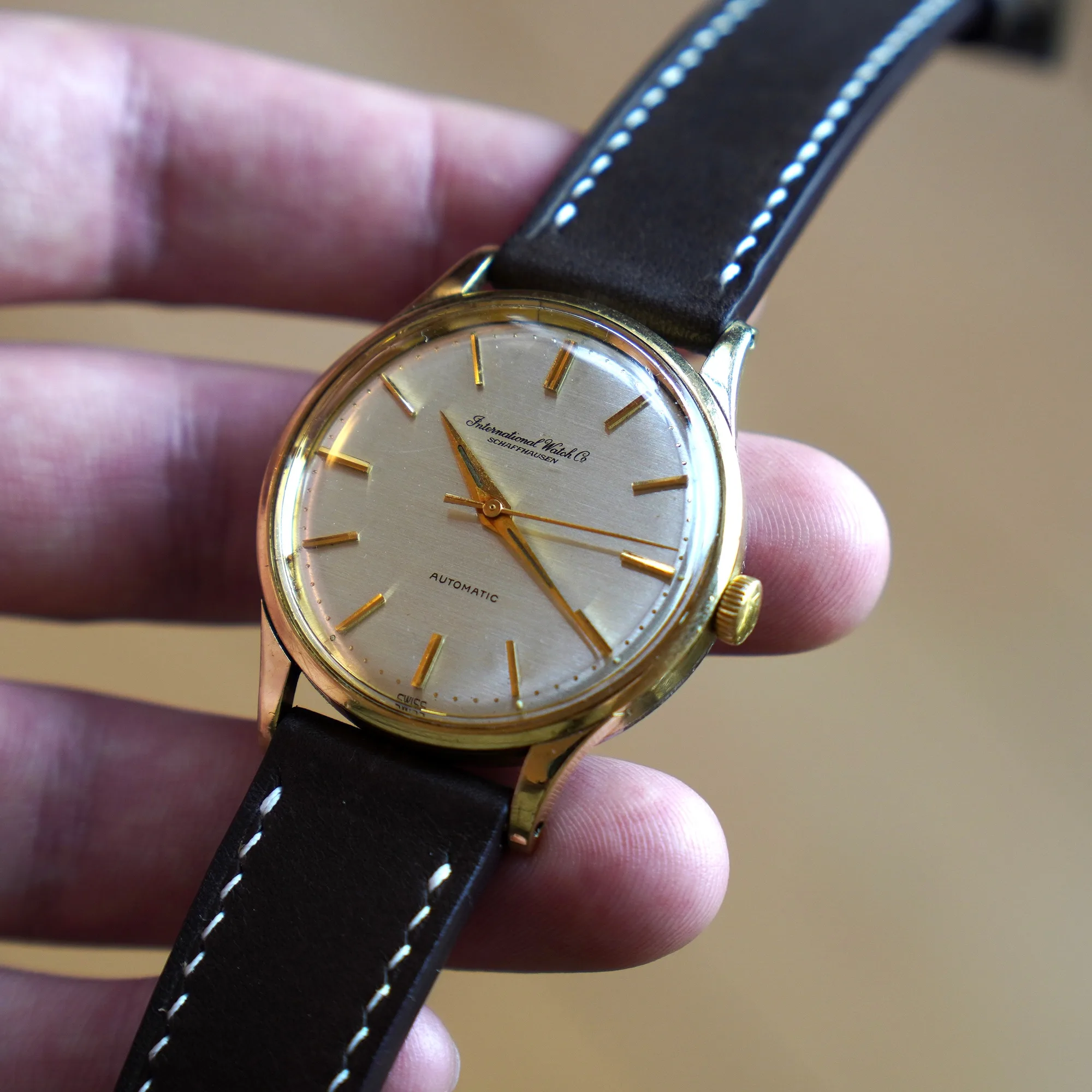 IWC Automatik 35 mm in der Hand gehalten, silbernes Zifferblatt mit Schriftzug International Watch Co Schaffhausen und goldenen Stabindizes